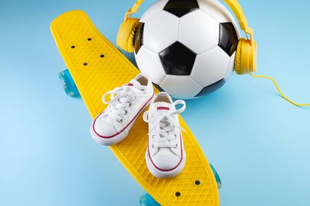 Yellow headphones, white sneakers and traditional style soccer ball over yellow background.の写真素材
