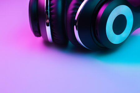 Retro 90s style photo of black stylish wireless headphone in neon lights.の写真素材