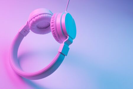 Retro 90s style photo of white stylish wireless headphone in neon lights. Music concept.の写真素材