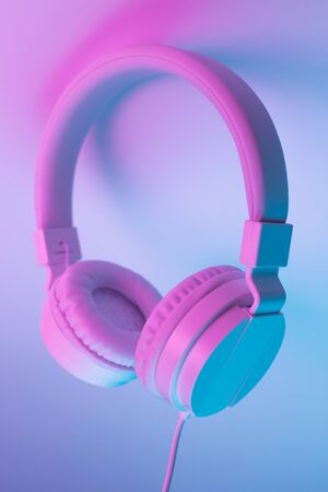 Retro 90s style photo of white stylish wireless headphone in neon lights. Music concept.の写真素材