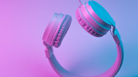 Retro 90s style photo of white stylish wireless headphone in neon lights. Music concept.の写真素材