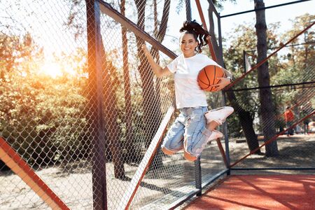 Careless brunette young woman with bright smile dressed in casual modern clothes jump with...