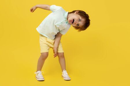 Adorable funny kid listening music and dance over yellow backgroundの写真素材