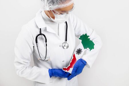 Doctor or nurse holding Italy map and flag. Coronavirus outbreak and pandemic concept. 2019-nCoV.の写真素材