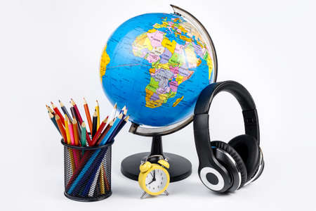 Earth globe model, headphone, clock and color pencils over white background. Back to school.の写真素材