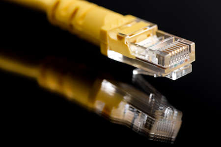 Macro image of yellow network plug over black background. Fiber optic.