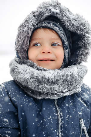 Portrait of amazed baby boy in a warm white snow suit.の写真素材