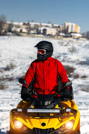 Close-up image of young man driver on the ATV quad bike stand in heavy snow with deep wheel track. Moto winter sports.の写真素材