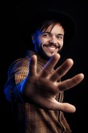 Handsome young bearded hipster in brown shirt over black background.の写真素材