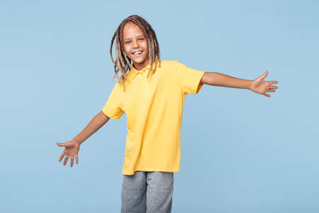 Happiness little boy with african dreads listening music in headphones dancing over blue background.の写真素材