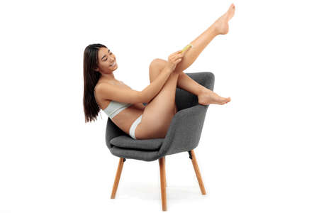 Beautiful asian young woman showing her soft skin after depilation procedure over white background.