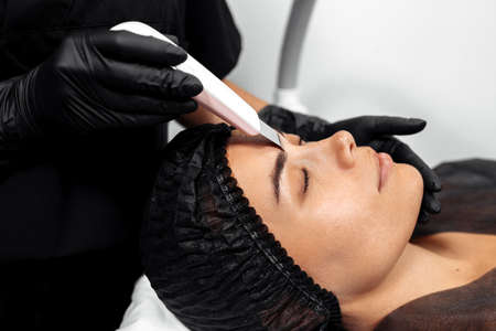 Cosmetologist make face while procedure ultrasound cavitation or facial peeling in cosmetology...