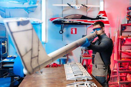 Young male engineer or technician testing simetry of drone details in lab. Aircraft capable of GPS...