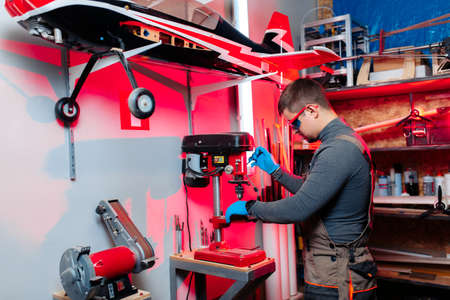 Young male engineer or technician using drill for drone details in lab. Aircraft capable of GPS...