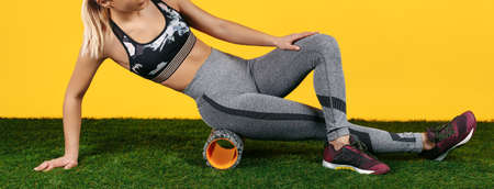 Close-up photo amazing fit young woman do exercise with foam roller on green grass over yellow...