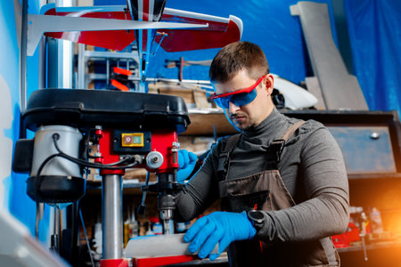 Young male engineer or technician using drill for drone details in lab. Aircraft capable of GPS...