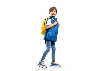 Full lengh image of a little boy with backpack walking over white background. Back to School....