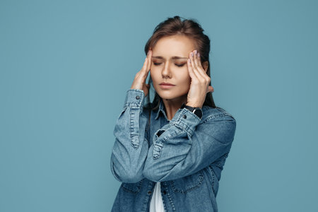 Pretty young woman got sick and headache on blue background.の写真素材