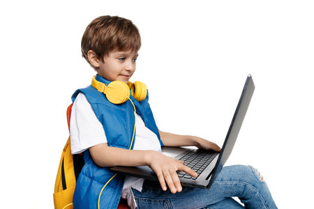 Smart blonde boy sitting on red chair and holding notebook on white background. Close-up imageの写真素材