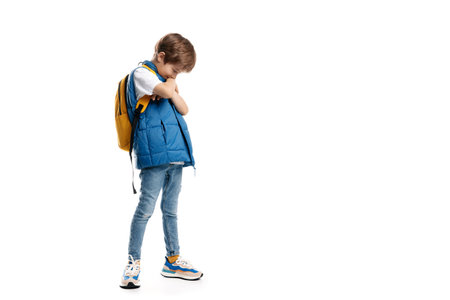 Little boy wearing yellow backpack looking away on white background. Back to Schoolの写真素材