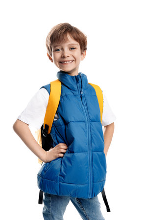 Cheerful little boy wearing yellow backpack looking away on white background. Smiling kid.