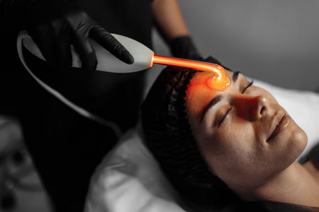 Cosmetologist makes the procedure electrotherapy of the facial skin of a beautiful.
