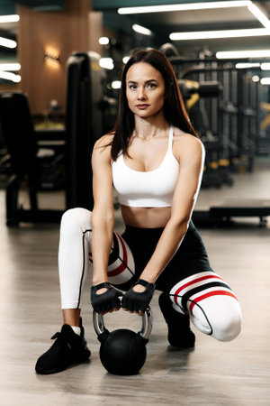 Sporty woman with perfect trained body resting after functional exercises with kettlebell at the gymの写真素材