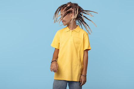 Happy little boy with dreads posing over blue background. Boy dancing
