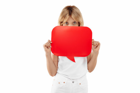 Attractive young blonde woman cover face with red blank speech bubble over white background