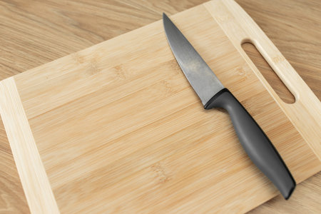 Sharp stainless steel kitchen knife resting on a wooden cutting board.の写真素材