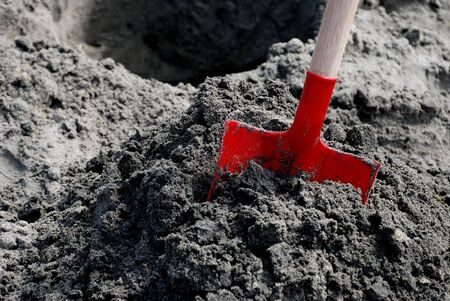Red Shovel in Sand with Hole