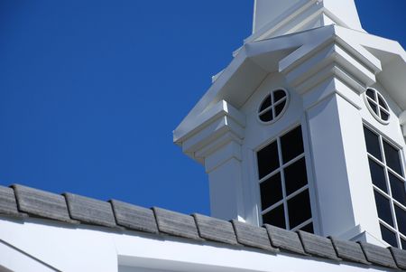 Detaill of a white church spire with dark windows taken against a deep blue sky.