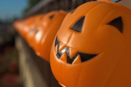 A row of brightly colored jack-o-lanterns hanging on a fence at halloweenの写真素材