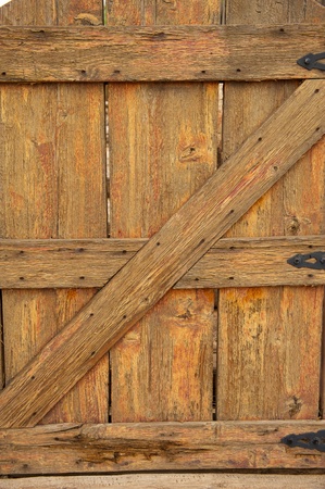 An old, weathered, worn, wooden gate with heavy grains, nail marks and black iron hingesの写真素材