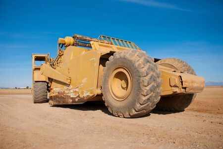 Profile of a Large Earth Mover Parked on a Dirt Lotの写真素材