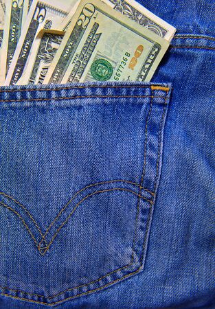 A back pocket of a pair of blue jeans full of currency in US Dollarsの写真素材