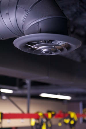 Black industrial air duct and vent or register hanging from an unfinished ceiling in a commercial space under constructionの写真素材