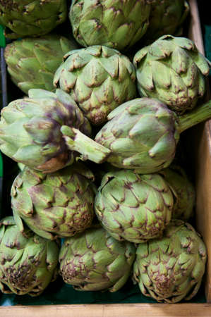 Fresh green artichokes in a wooden bin in a grocery store produce departmentの写真素材