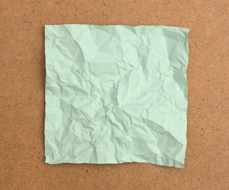 Crumpled green note paper isolated on brown boardの写真素材