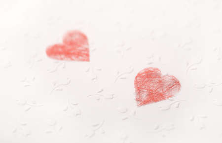 Red paper hearts on the white paper with flowersの写真素材