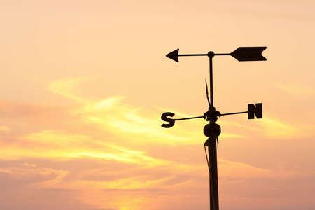 Silhouette of a weathervane over orange evening skyの写真素材