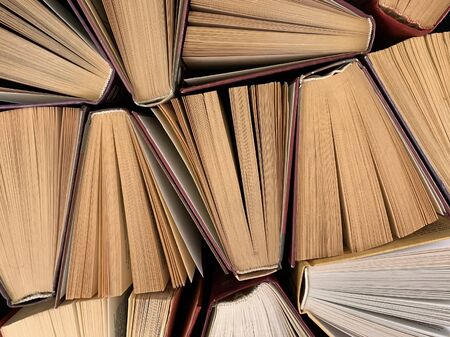 Background texture: ajar pages of books. Old hardback textbooks, on black background. Concept:...
