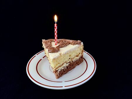 Round cake with candles, on a black background. A sweet birthday present for a teenager. A festive dessert for the whole family. Cream cake and multi-colored candles.の写真素材