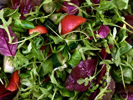 Vegetable salad of cucumbers, tomatoes and herbs on a black background. Finely chopped vegetables in a salad bowl, close-up. Concept: healthy eating, fresh vegetables, healthy vitamins.の写真素材
