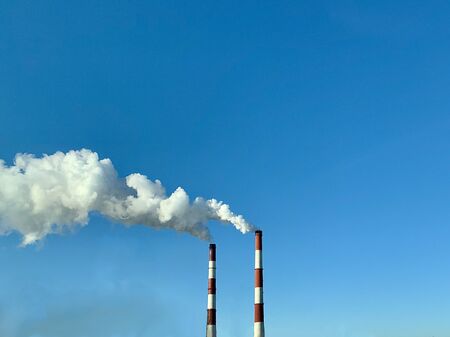 Smoke from industrial chimneys against a blue sky. Smoke from factory chimneys in an urban...