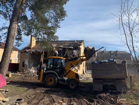 Heavy equipment near the destroyed brick house. Construction machinery on the background of the...