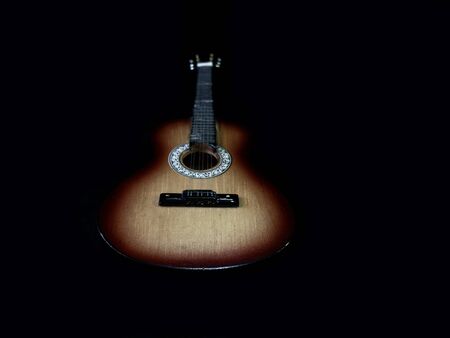 Six-stringed acoustic guitar on a black background. Musical string instrument. Guitar fretboard with...