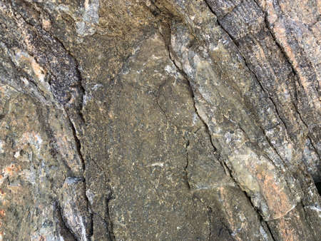 Background texture: the structure of a large stone. Granite boulder close up. Irregularities and...