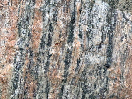 Background texture: the structure of a large stone. Granite boulder close up. Irregularities and...