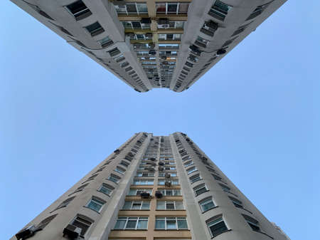 Multi-storey building against the blue sky. Tall new building with mirrored windows, bottom view....